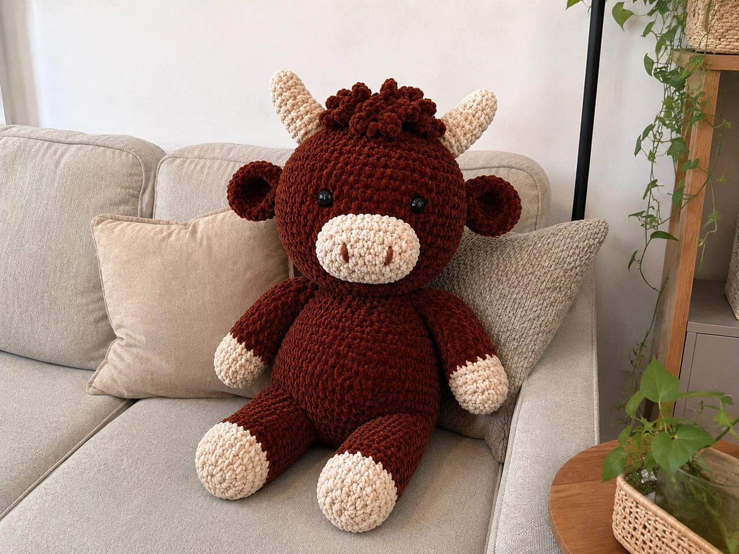 Large crochet Highland cow plush displayed on sofa as cozy home decor