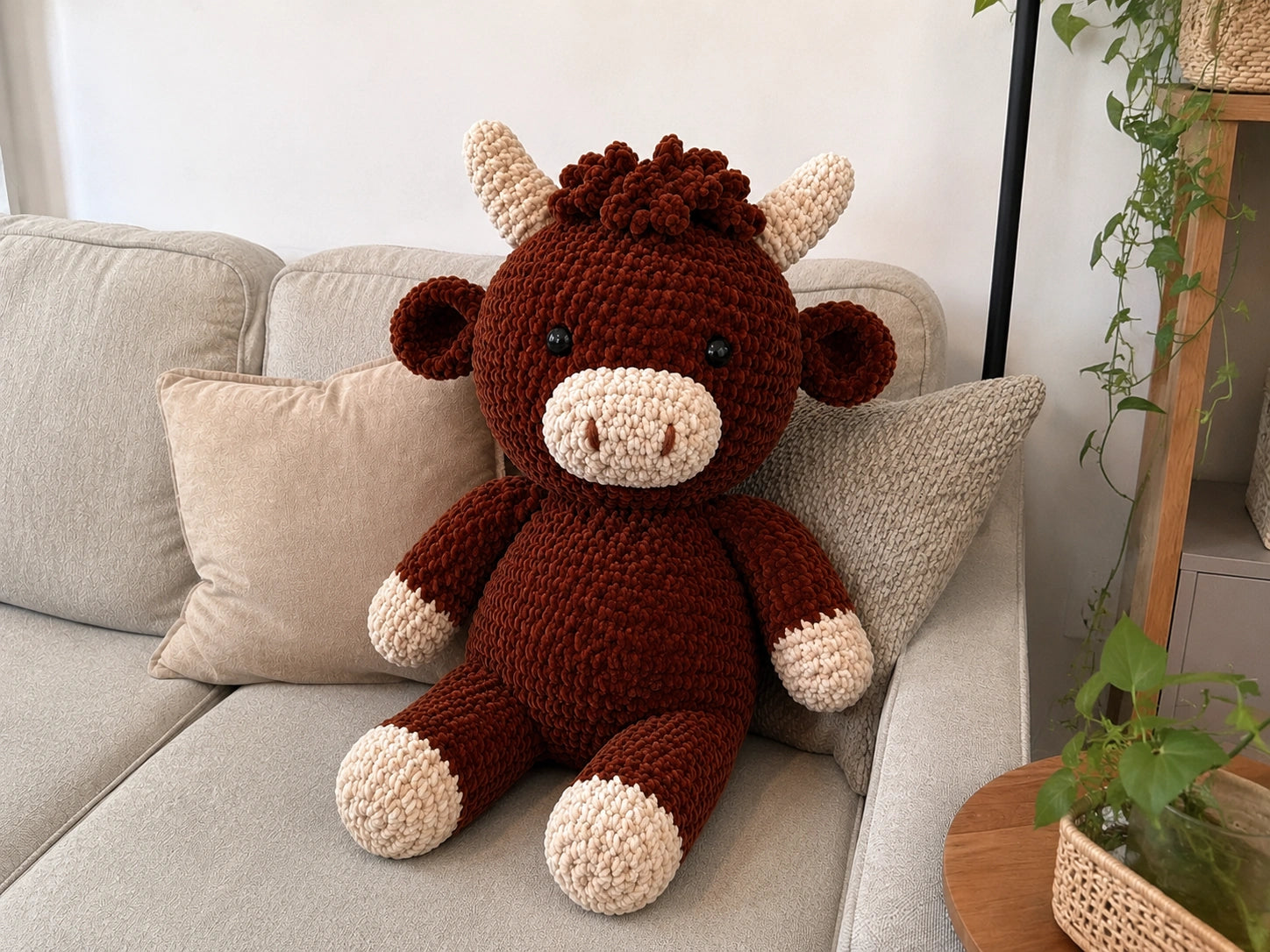 Large crochet Highland cow plush displayed on sofa as cozy home decor